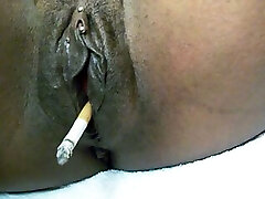grosse chatte noire brillante fumant une cigarette sur webcam