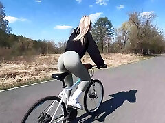 Ash-blonde cyclist shows peach buddy to her partner and drills in public park