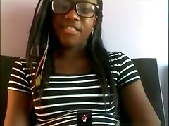 Black egghead with glasses milks with a hairbrush on her bed on skype