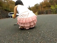 Azjatycka nastolatka pochyla się i pokazuje napalone pod spódniczkę na ulicy