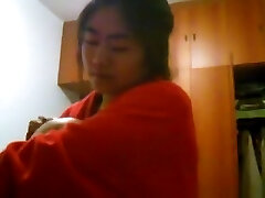 Asian girl with big fun bags changes clothes in her bedroom