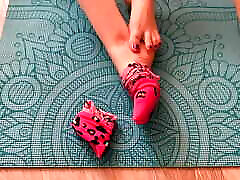 Gloria Gimson in pink socks caresses her feet on a yoga mat