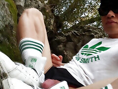 Gay twink pulls his cock out of his shorts, jerks off, and ejaculates cum on his Adidas Stan Smith sneakers in the mud outdoors
