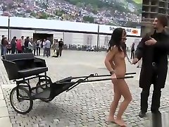 Naked brunette chick harnessed to cart in a public cospla butt