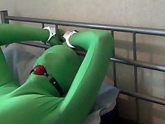 tied up and ball gagged in green hairless boobs zentai bodysuit
