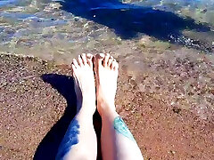 डॉमीनेटरिक्स नीका अपने पैरों पर नमकीन समुद्र का आनंद लेती है ।