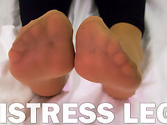 Mistress feet in soft nylon socks is resting on the bed