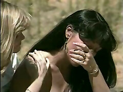 A blonde and a brunette go lesbian in a tent in retro porn clip