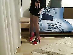 transexual milf mostrando y tocando frente a la cámara con un vestido de satén negro, medias de red y tacones