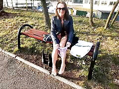 她尿尿通过裤子和闪烁在一个公共公园
