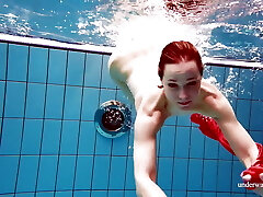 可爱的女孩在红色性感的开放式礼服游泳