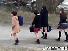 Four Japanese schoolgirls dork around outside before peeing
