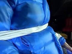 сексуальная пия, связанная веревками и с матерчатым кляпом во рту, сидит в парикмахерском кресле в сексуальных синих блестящих нейлоновых дождевиках и светло-голубой пуховой рубашке видео