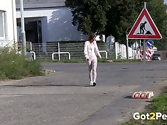 Dirty black haired chick pisst in der Nähe der Straße unterzeichnen eine Menge